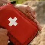 Hände öffnen ein Erste-Hilfe-Set im Freien