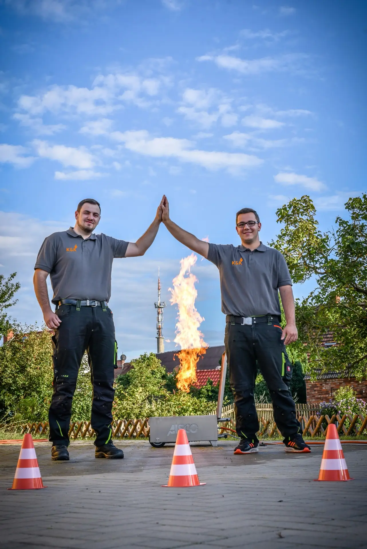 Zwei Mitarbeiter beim High-Five vor einem Übungsfeuer